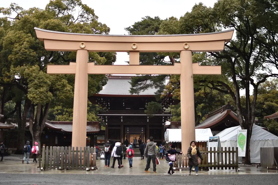 Visitors walking through the large wooden torii gate at Meiji Shrine in Tokyo
