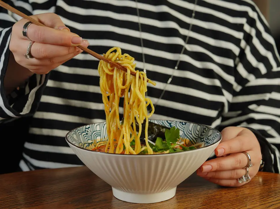 Close-up of someone eating ramen with chopsticks