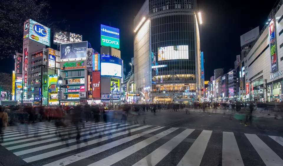 Shibuya Crossing in Tokyo at night, lit by big screens