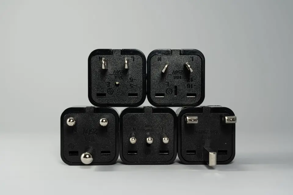 A pile of black international plug adapters