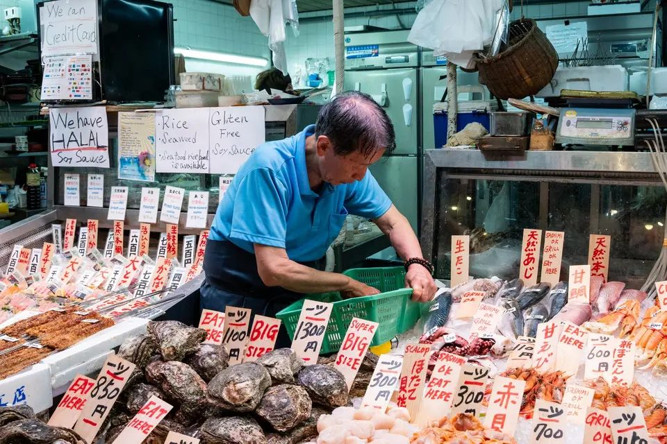 A vendor arranging fresh seafood at a Japanese market stall